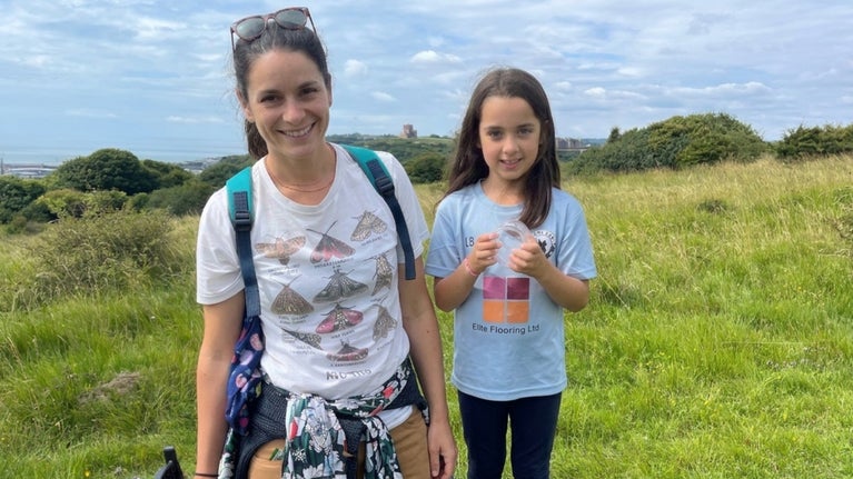 Image of a mother and child hunting for bugs at the White Cliffs of Dover on a sunny day